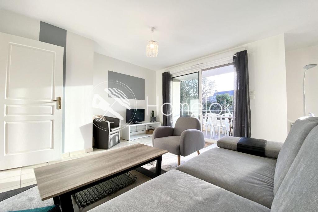 una sala de estar con un sofá y una mesa en Joli T3 super cosy À 2 pas des plages, en Ploemeur