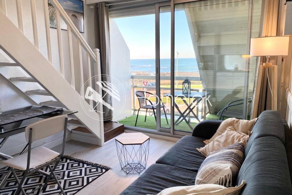 Una sala de estar con un sofá y vista al mar. en Joli appartement Cocooning Vue mer 180, en Ploemeur