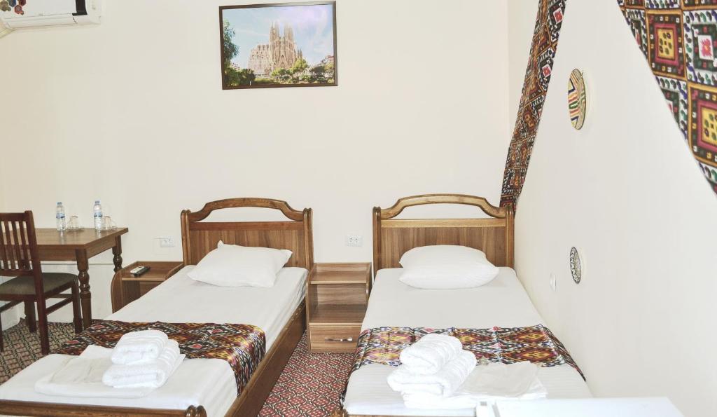 two beds in a room with a desk and a table at Elegant Hotel in Tashkent