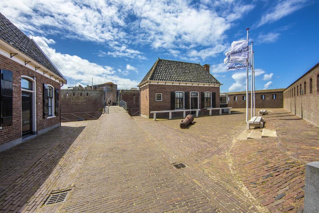 an empty courtyard of a brick building with a flag at Fortwachterswoning in Huisduinen