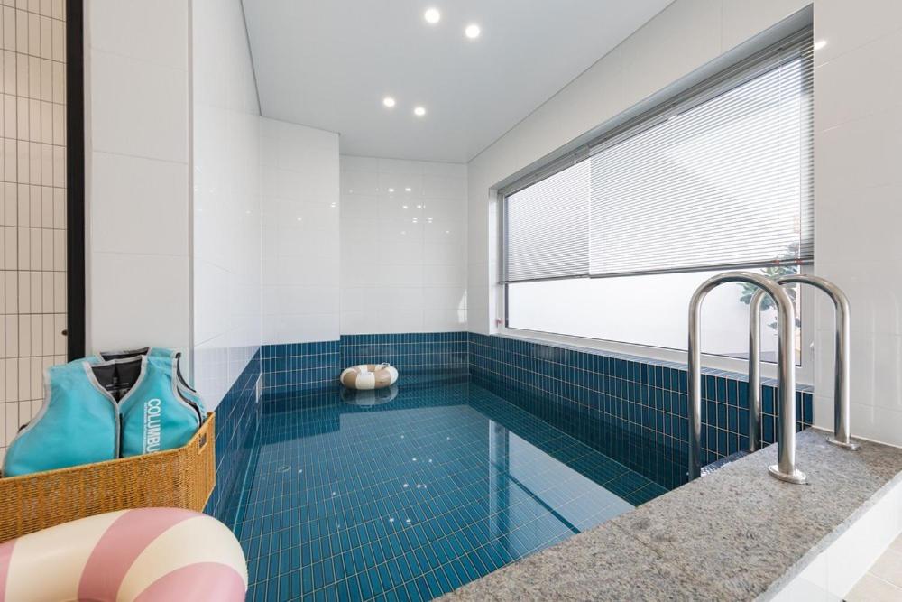 a bathroom with a swimming pool with blue tiles at Gangneung Dao Pool Villa in Gangneung