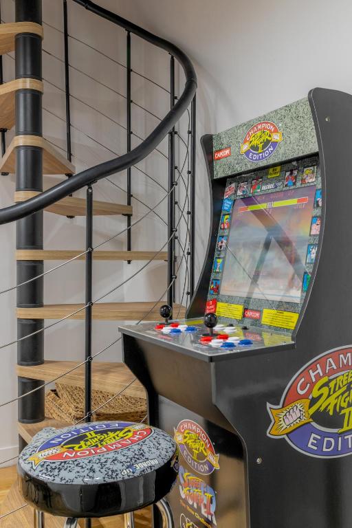 Un flipper est installé à côté d'un escalier en colimaçon. dans l'établissement An Enchanting Parisian hideaway, à Paris