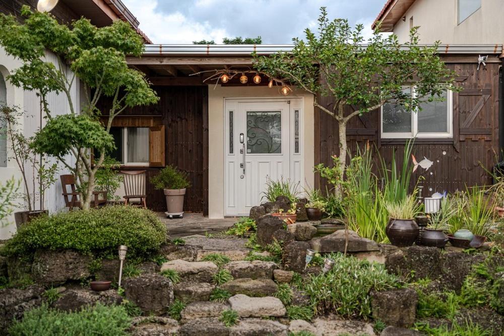 a house with a white door and a stone walkway at Jeju Wooden Attic Pension in Namŭm-ni