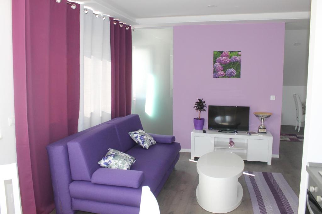 un soggiorno con divano viola e TV di Apartments Floki a Cavtat