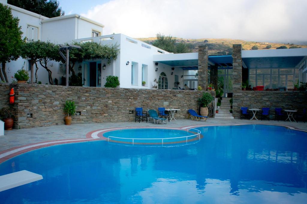 a blue swimming pool in front of a house at Aiolos Hotel Andros in Ménites