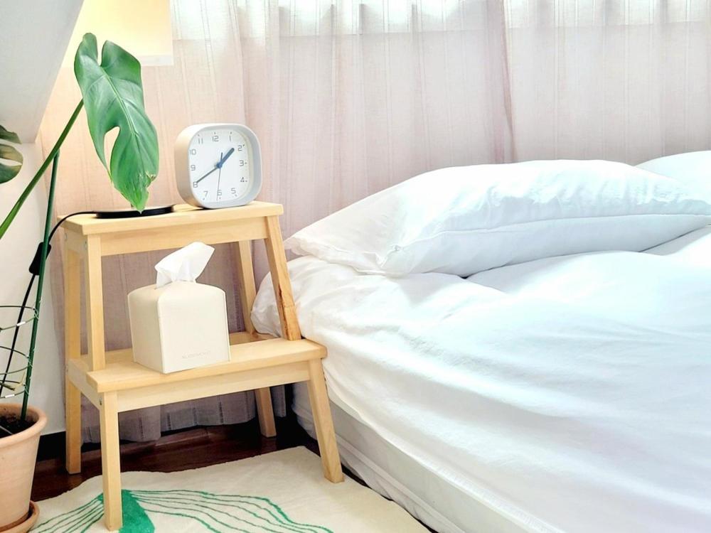 a clock on a night stand next to a bed at Jeju Hyeopjae Life in Jeju