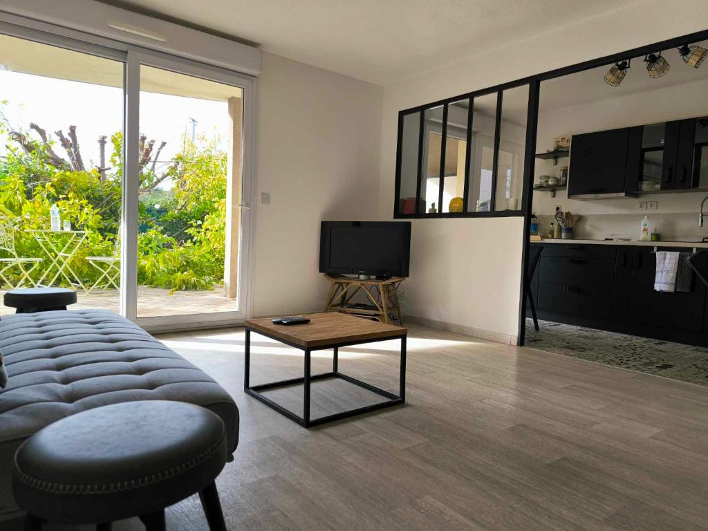 un salon avec un canapé, une télévision et une table dans l'établissement T2, 10min centre historique, clim, jardin, parking, à Avignon