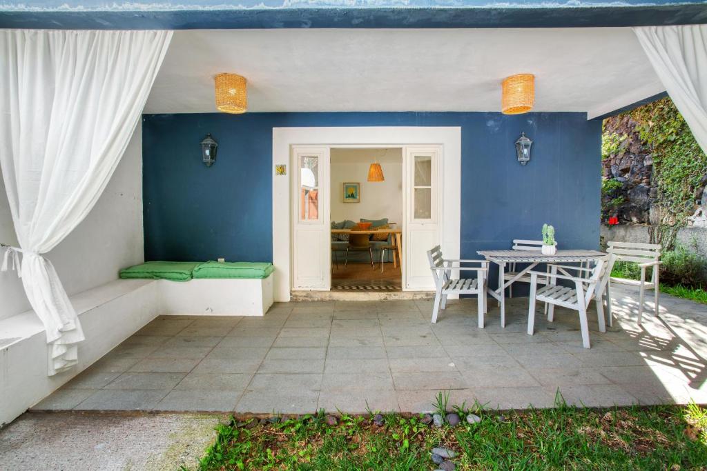 un patio con tavolo, sedie e parete blu di Calheta Beach House T1 a Calheta