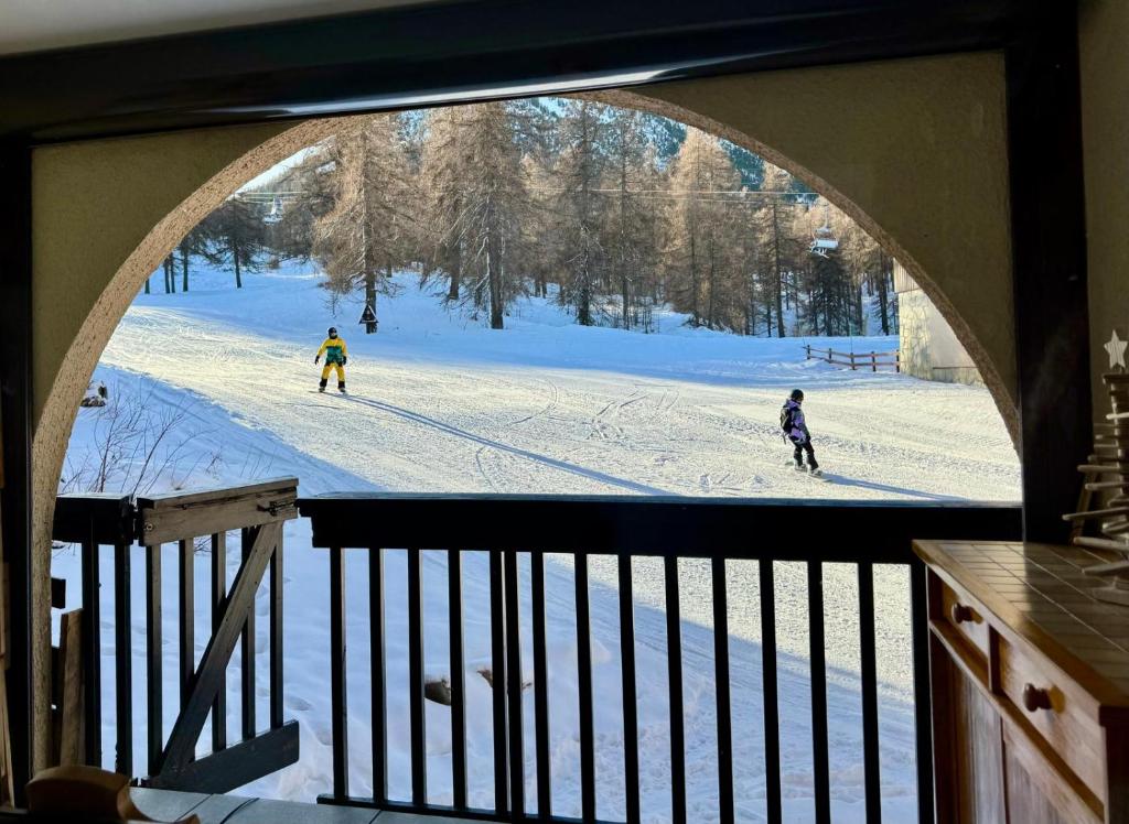 2 personnes font du ski sur une piste enneigée dans l'établissement Evasion Unique Ski au Pieds, à Montgenèvre