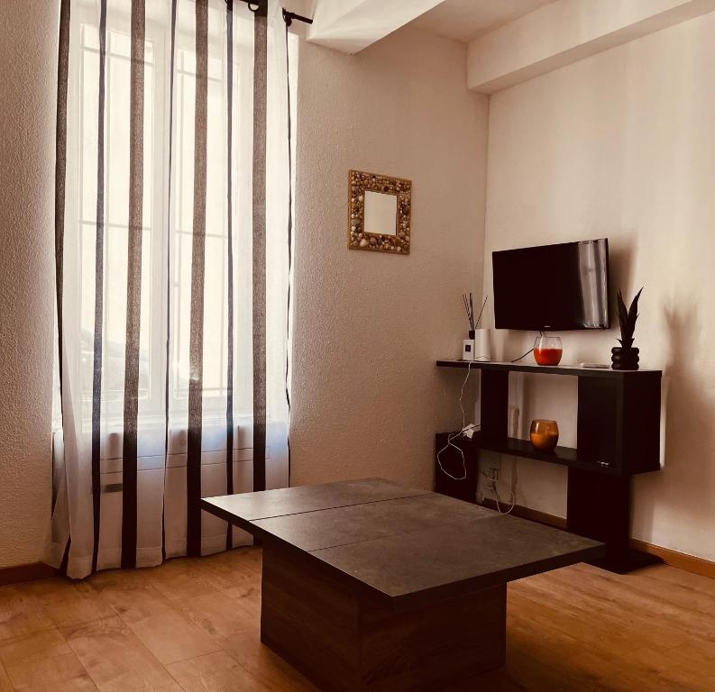 un salon avec une table basse et une télévision dans l'établissement Cosy BEFFROI, à Narbonne