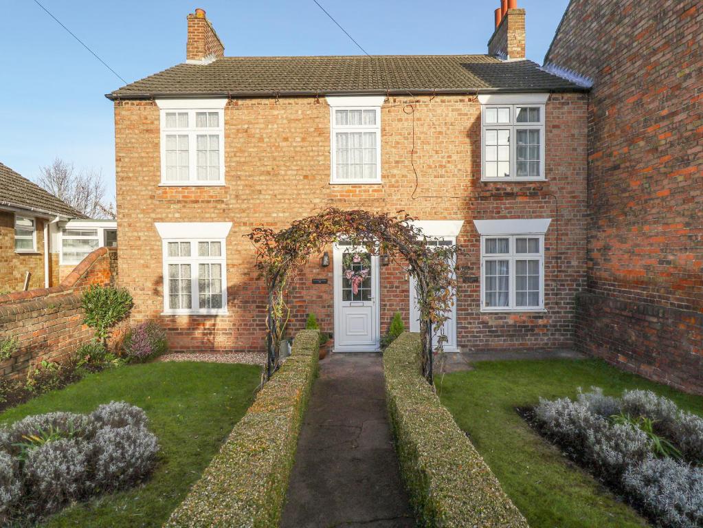 a brick house with a white door and a yard at Lavender Cottage in Louth