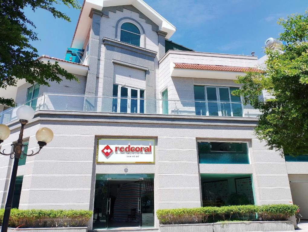 un edificio con un cartello rosso alle erbe di fronte di Red Coral Hotel a Phan Rang-Tháp Chàm