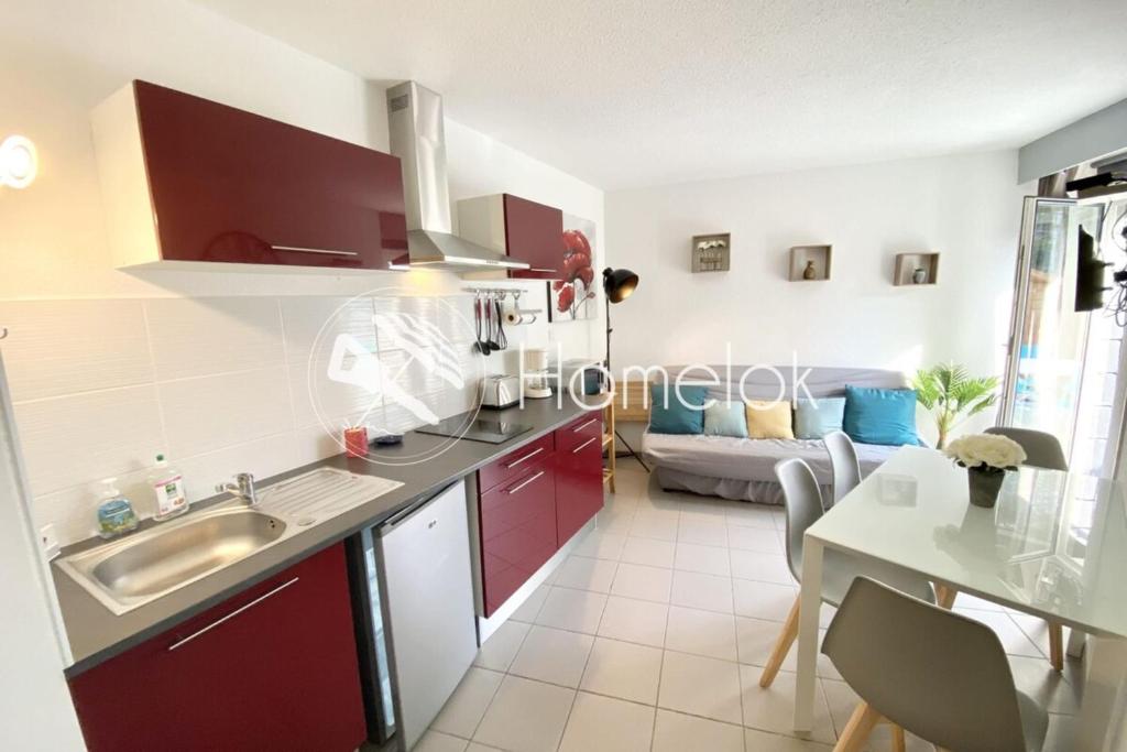 - une cuisine avec des placards rouges, une table et un canapé dans l'établissement Maisonnette Ultra cosy Bord de mer Terrasse, à Guidel