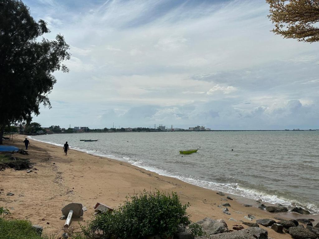 a beach with a person and a boat in the water at Seaside 4 Bedroom House at PD by MAISON in Port Dickson
