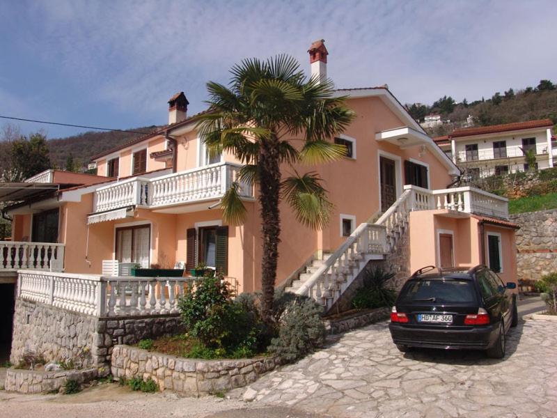 a car parked in front of a house with a palm tree at Apartments Kristic in Lovran