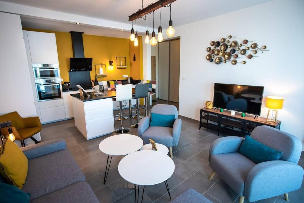 un salon avec des canapés et des tables ainsi qu'une cuisine dans l'établissement L Olympe Terrasse Parking Wifi, à La Rochelle