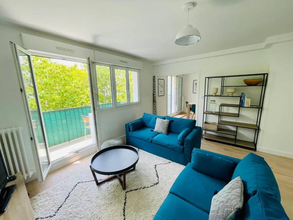 un salon avec un canapé bleu et une table dans l'établissement Le Cordeliers Confort - Parking Wifi, à La Rochelle