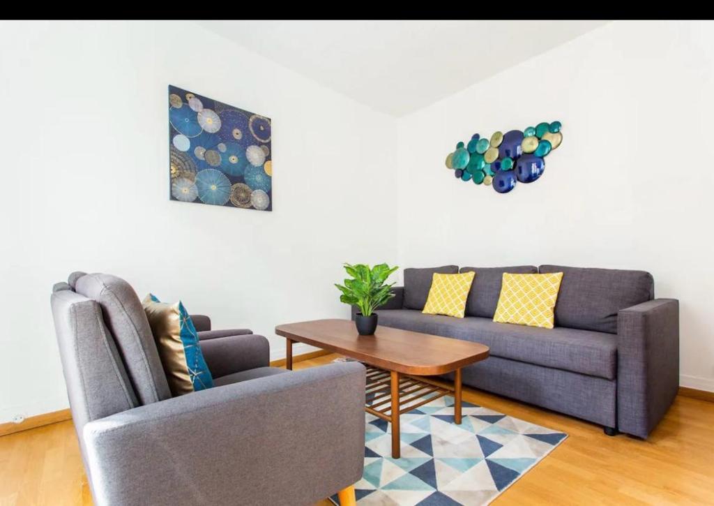 un salon avec un canapé et une table dans l'établissement Le Raspail - Charmant appartement proche Paris, à Levallois-Perret