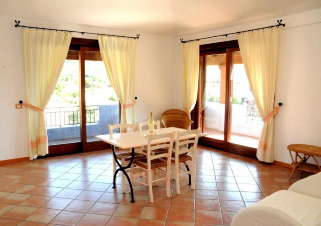 a dining room with a table and chairs and windows at Marinella Residence in Santa Marinella