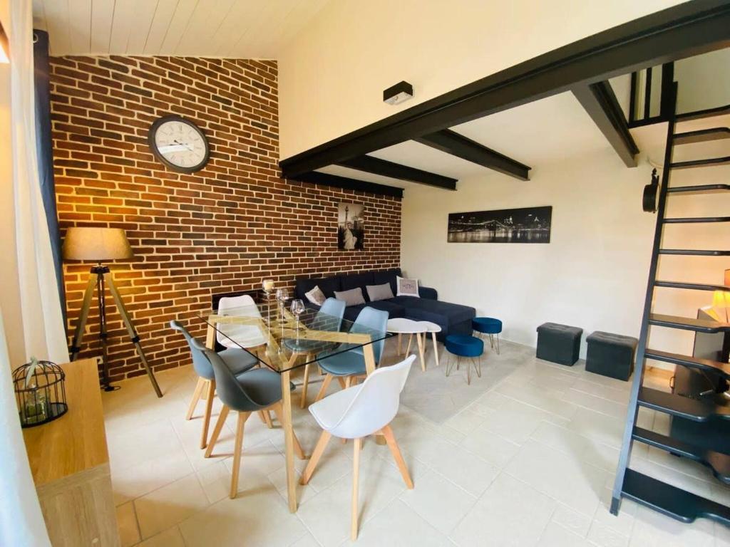 - un salon avec une table et des chaises ainsi qu'un mur en briques dans l'établissement La Madeleine - Maison de Ville Moderne - Terrasse, à La Rochelle