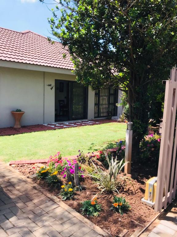 a garden in front of a house with flowers at La Gracia Guesthouse in Vanderbijlpark