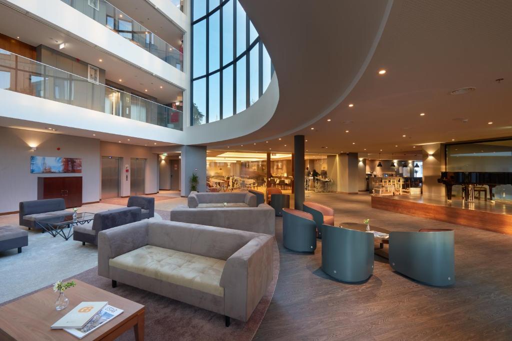 eine große Lobby mit Sofas und Tischen in einem Gebäude in der Unterkunft Eurostars Heroismo in Porto