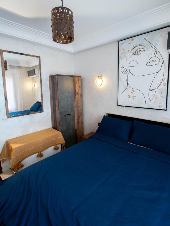 une chambre avec un lit bleu et un miroir dans l'établissement Cozy I Victor Hugo, à Marrakech