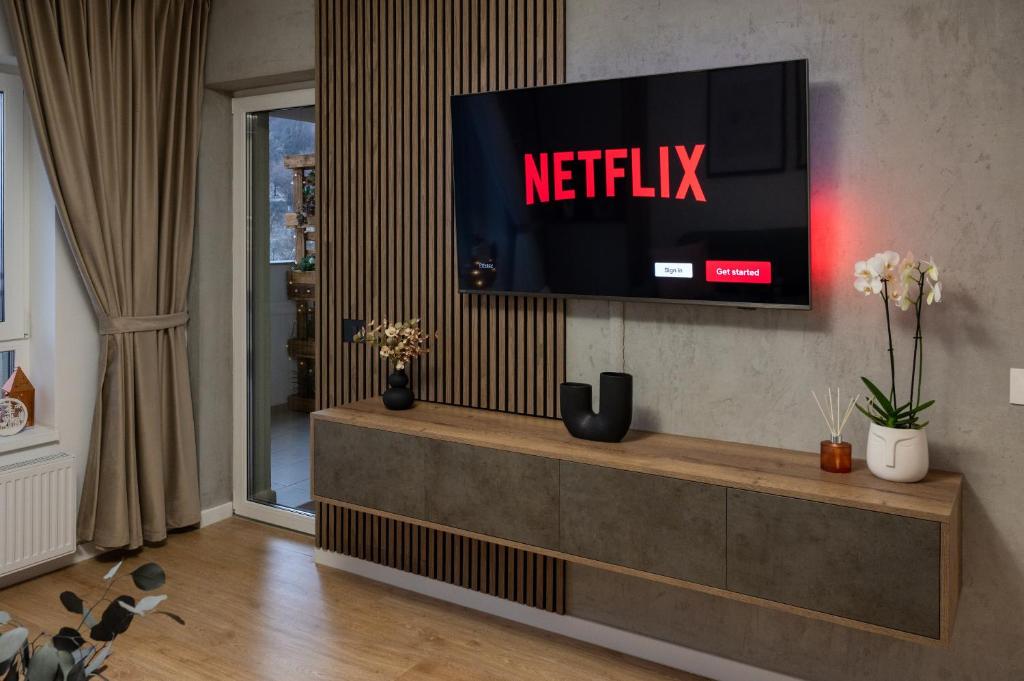 un salon avec une télévision sur un mur dans l'établissement Mountain and City View with Underground Parking, à Braşov