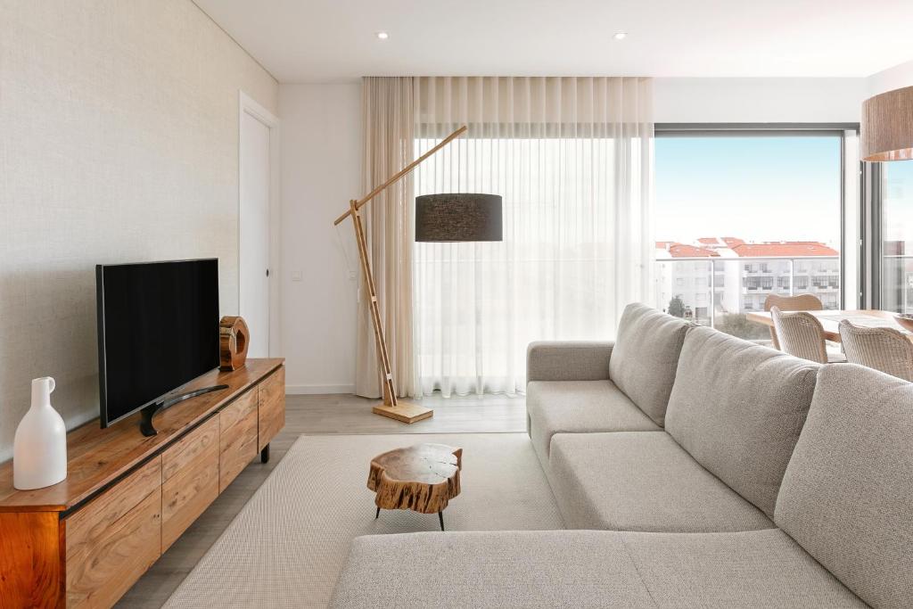 ein Wohnzimmer mit Sofa und Flachbildfernseher in der Unterkunft Consolação Sunset View in Atouguia da Baleia