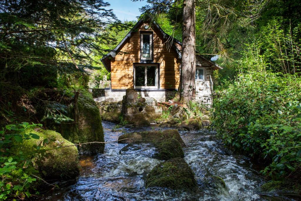 an old cabin in the woods next to a stream at Moulin De Villesaint in Faux-la-Montagne