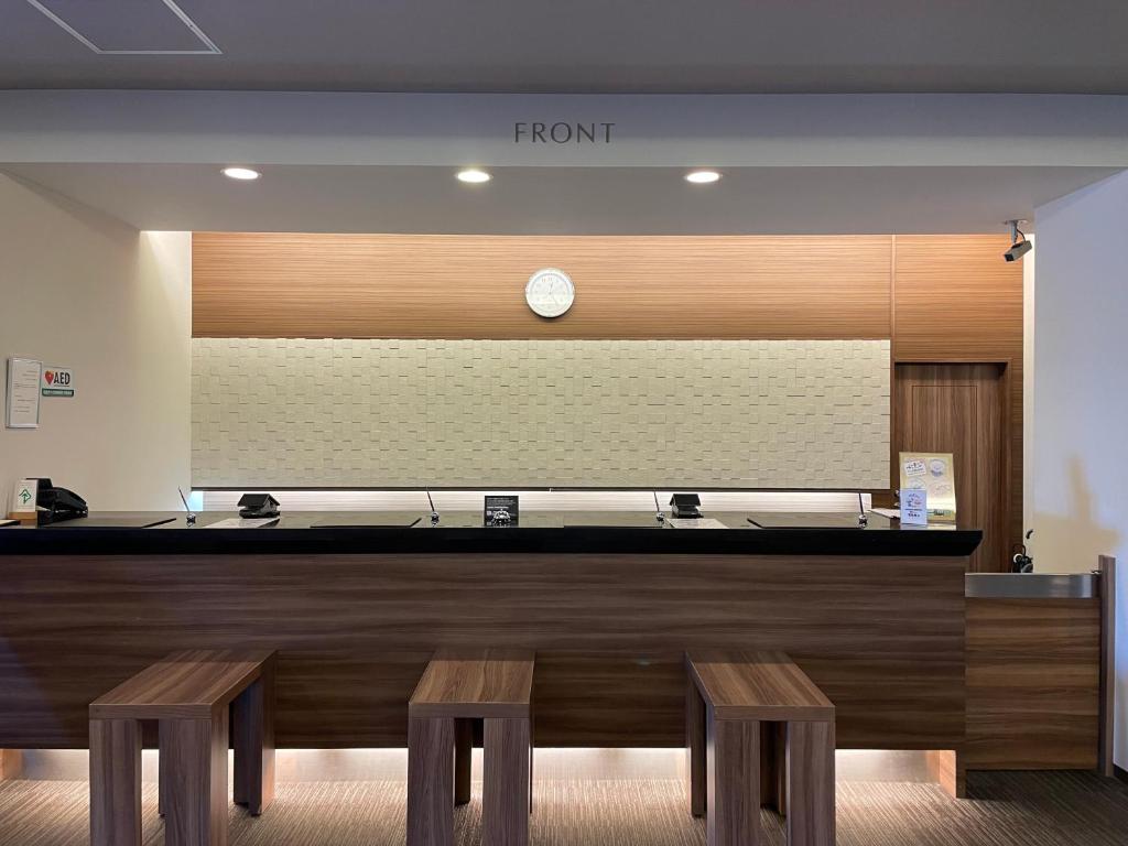 a front desk with two benches and a clock at Hotel Route-Inn Miyako in Miyako