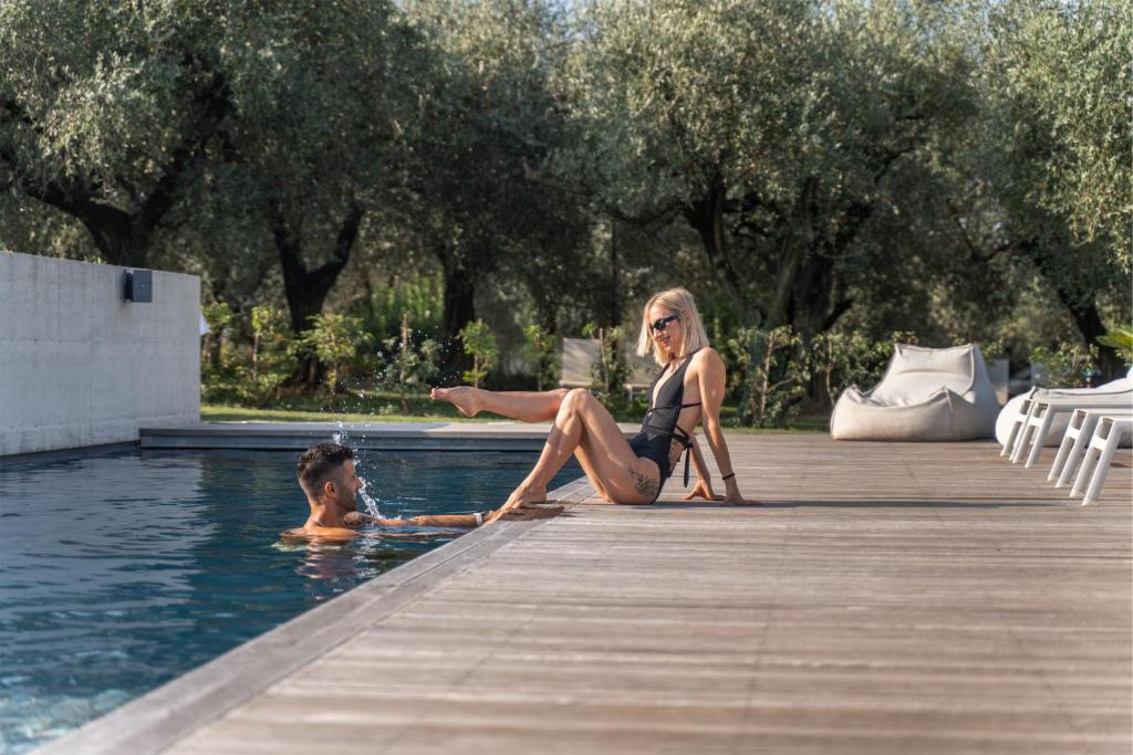 a woman sitting next to a boy in a swimming pool at OLEEVA Garda Living - Adults Only in Riva del Garda