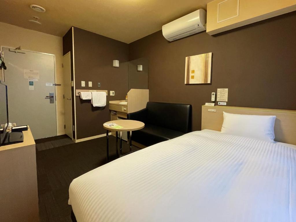 a hotel room with a bed and a chair at Hotel Route-Inn Miyako in Miyako