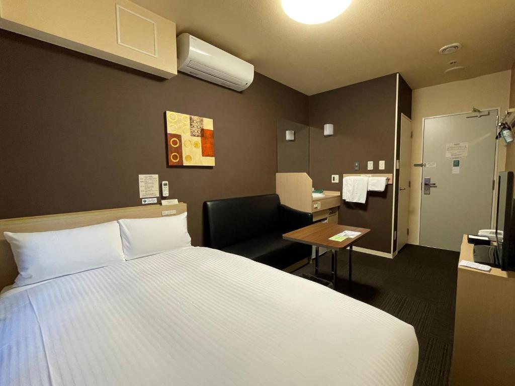 a hotel room with a bed and a chair and a desk at Hotel Route-Inn Miyako in Miyako