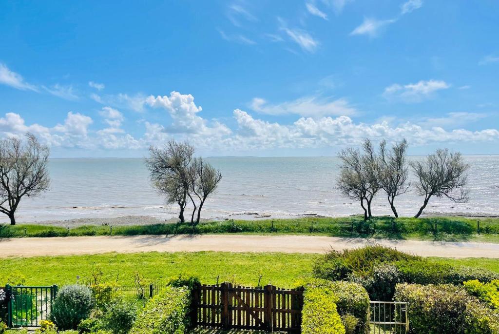 - une vue sur la plage avec des arbres et l'océan dans l'établissement La Canopee - Beau T3 Vue Mer Imprenable, à La Rochelle