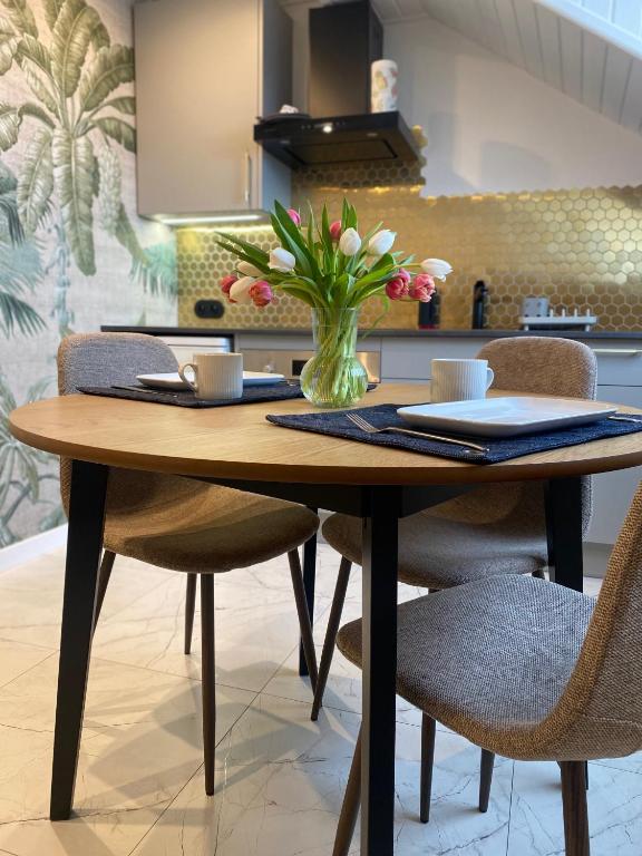 a dining room table with a vase of flowers on it at Apartamenty Plac Moniuszki 11 City Center in Kielce