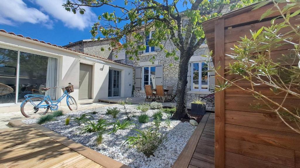 un jardin avec un vélo bleu en face d'une maison dans l'établissement L Armada - Maison 3 Chambres - Terrasse Wifi, à La Rochelle