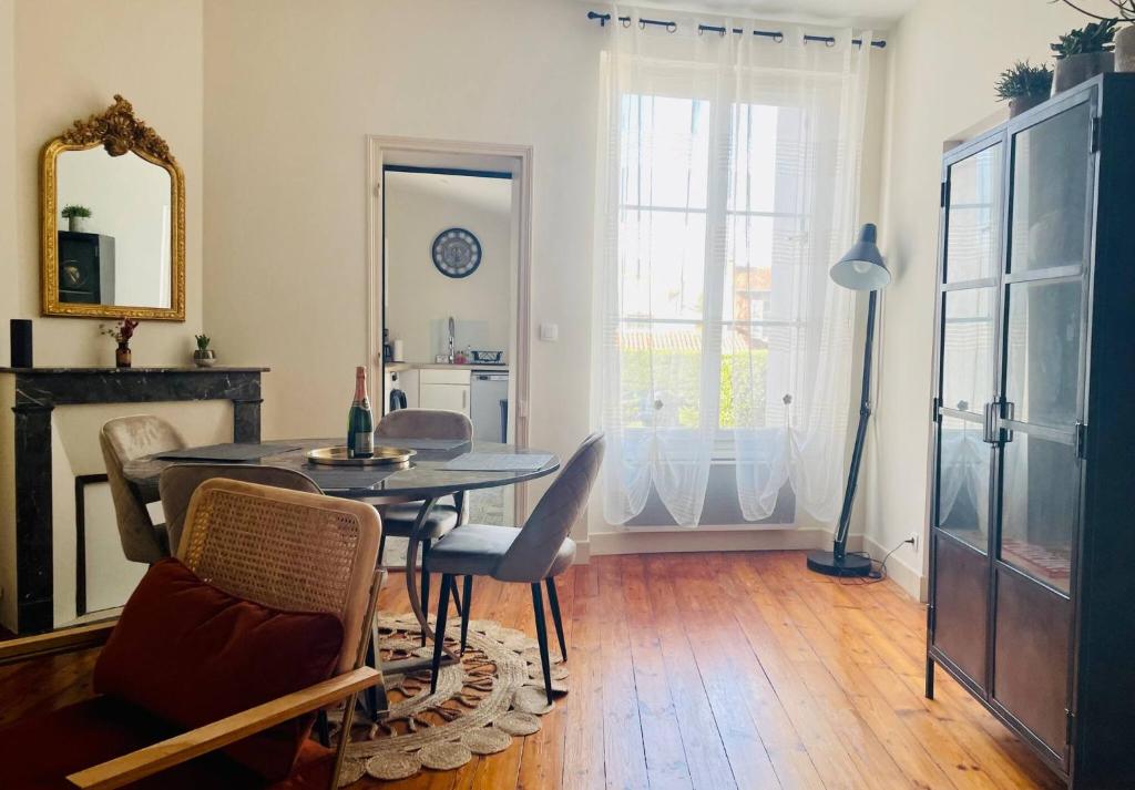 une salle à manger avec une table, des chaises et un miroir dans l'établissement Appartement de Standing - Le Henri Jeanne 1910, à La Rochelle
