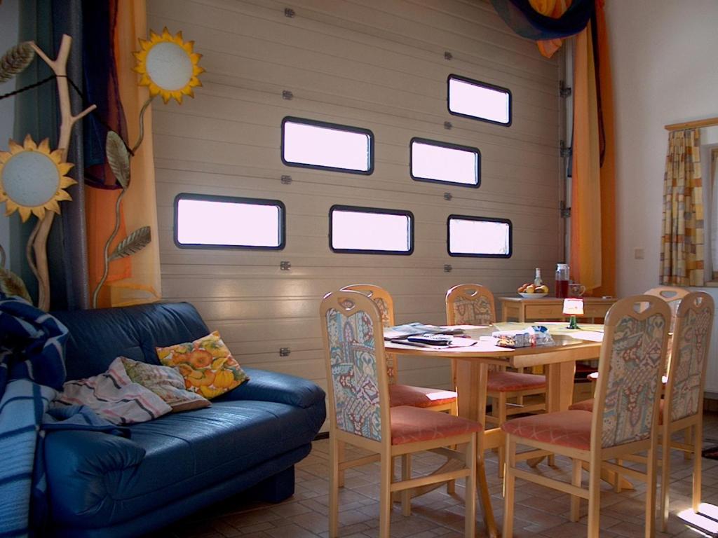 ein Wohnzimmer mit einem Tisch, einem Sofa und Fenstern in der Unterkunft Abenteuerhof in Weißenbach