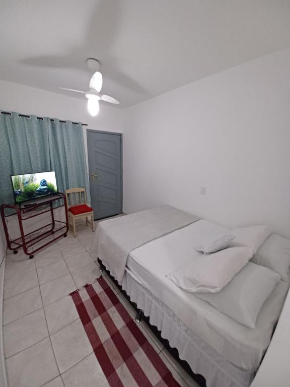 a white bedroom with a bed and a television at Arraial do Cabo - Flat Paraíso II in Arraial do Cabo