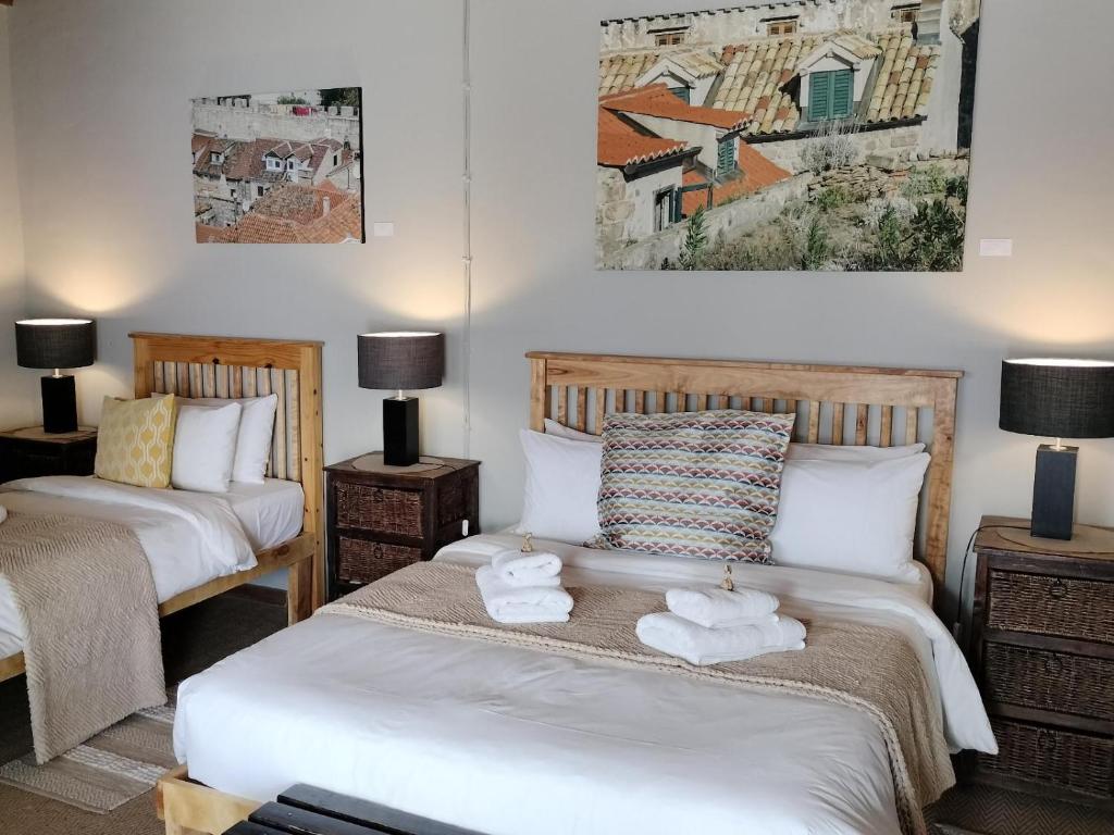 two beds in a room with two lamps and towels at Rusgenot - Richmond, Karoo in Richmond