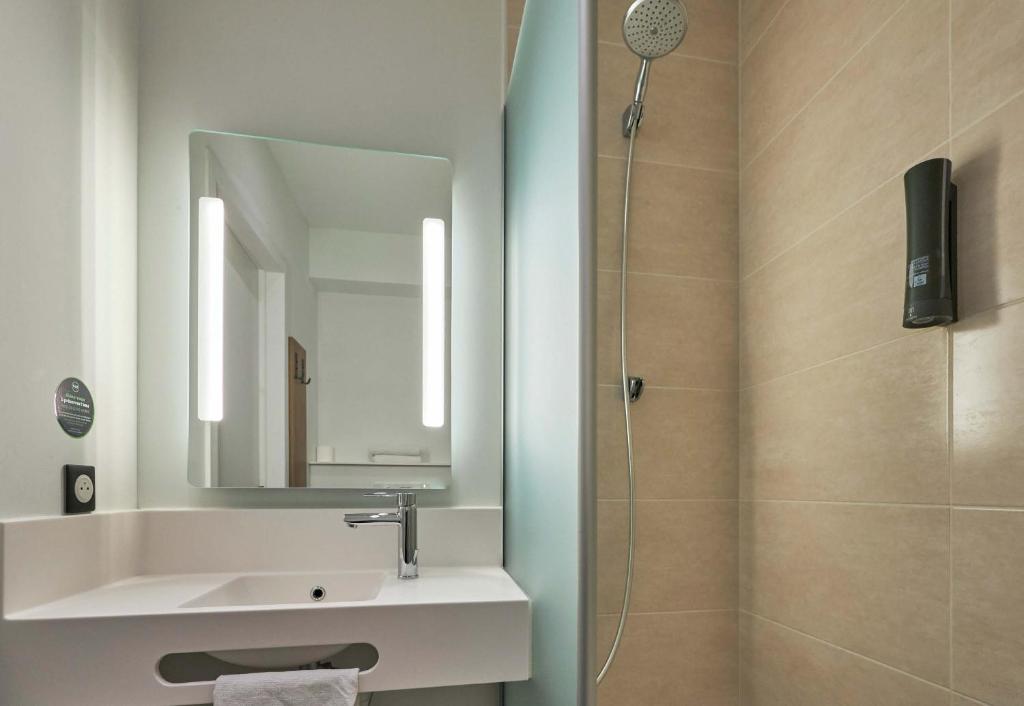 a bathroom with a sink and a shower with a mirror at B&B HOTEL Ouistreham in Ouistreham
