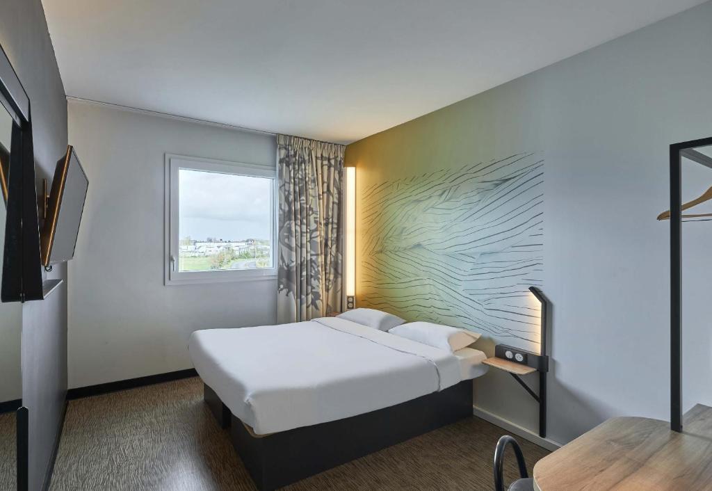 a hotel room with a bed and a window at B&B HOTEL Ouistreham in Ouistreham