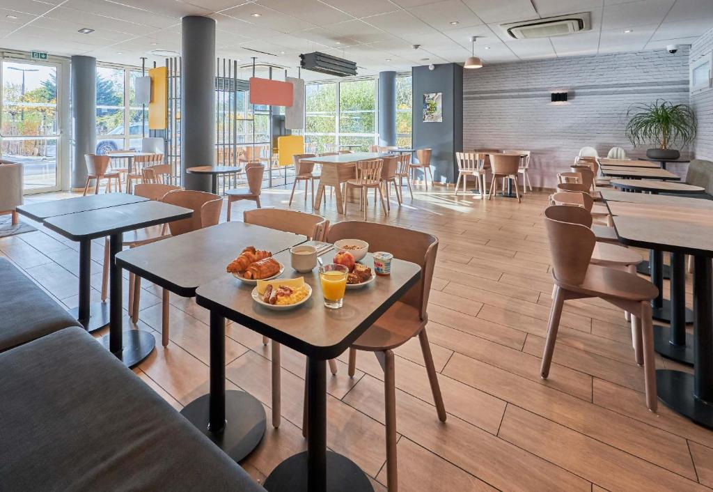 a restaurant with tables and chairs with food on them at B&B HOTEL Ouistreham in Ouistreham