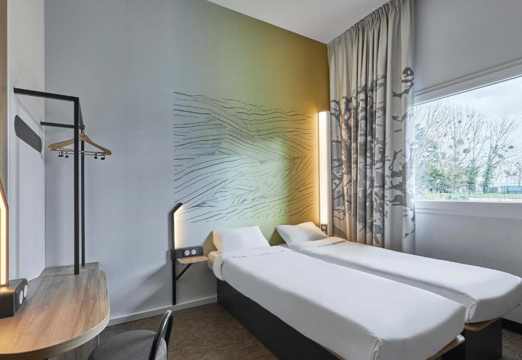 a room with a bed and a table and a window at B&B HOTEL Ouistreham in Ouistreham