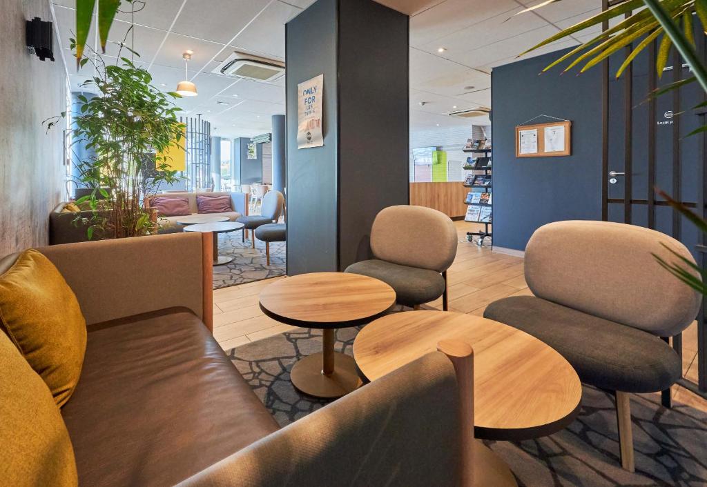 a waiting room with couches and chairs and tables at B&B HOTEL Ouistreham in Ouistreham