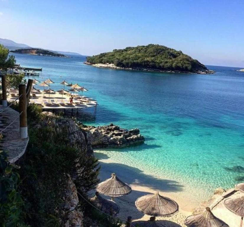 a beach with umbrellas and an island in the water at Vila Oscar in Ksamil