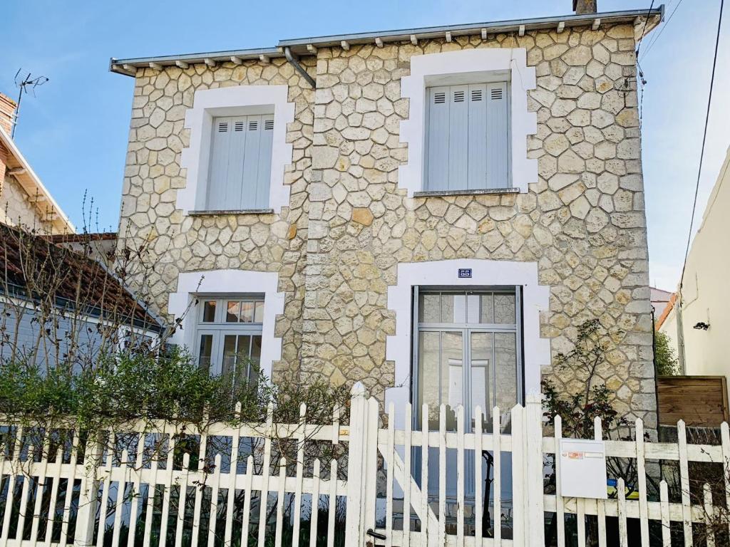 une maison en pierre avec une clôture blanche dans l'établissement Maison 3 chambres avec cour privative, à La Rochelle