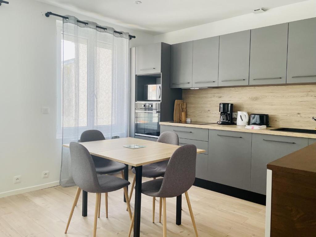 une cuisine avec une table et des chaises dans une pièce dans l'établissement La Petite Fonderie 2eme etage - Bel Appt Centre Ville Lr Wifi, à La Rochelle