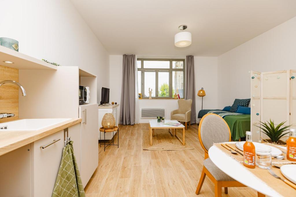 Una cocina y una sala de estar con una mesa y una sala de estar. en Résidence de Charleville-Mézières, en Charleville-Mézières